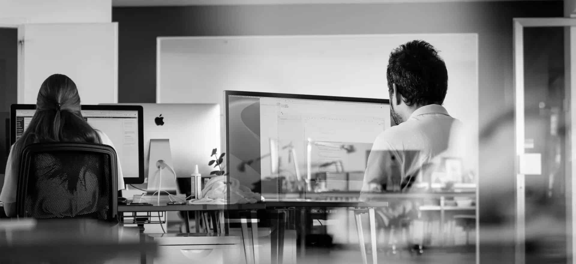 Deux personnes travaillant devant des ordinateurs dans un bureau | Ergopix Sàrl